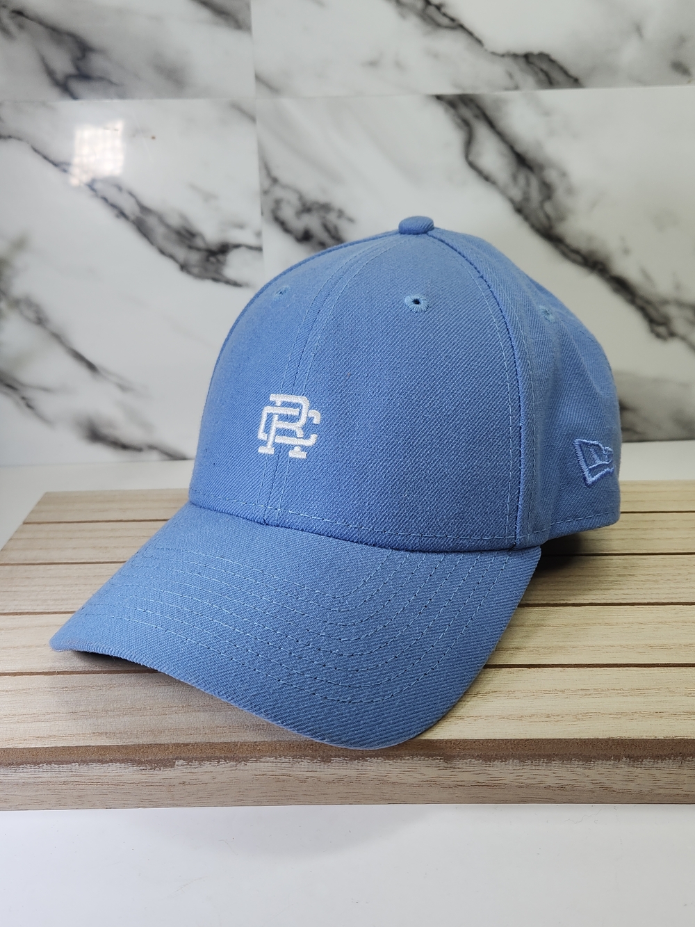 Reigning Champ New Era Sky Blue Baseball Cap with White Monogram. RC.